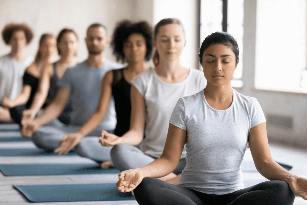 A group of people meditating on the beach at sunset